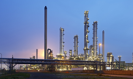 An oil refinery with pipeline bridge in the harbor of Antwerp with night blue sky.